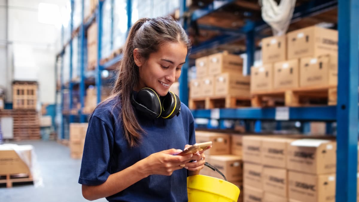 young female coworker using smartphone in the warehouse