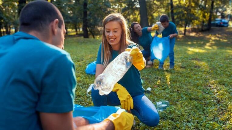 Colleagues collecting plastic bottles in a park